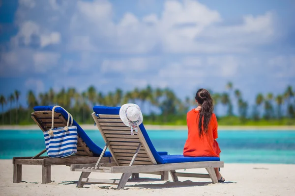 Bakifrån av ung kvinna avkopplande på solstolar — Stockfoto