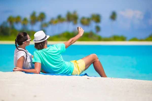 Young happy couple making a selfie with mobile phone on beach — Stock Photo, Image