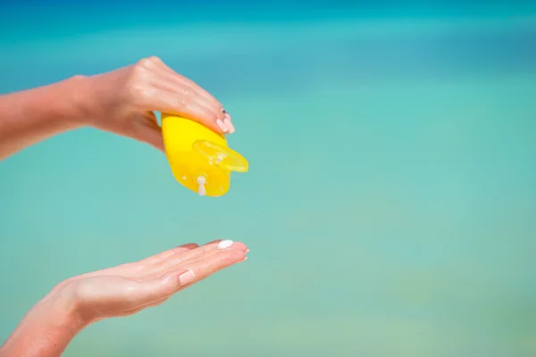 Female hands with suncream bottle background blue sea — Stock Photo, Image