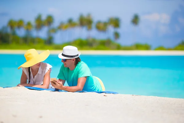 Young happy couple with mobile phone on beach — Stock Photo, Image