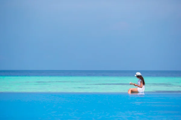 Young girl reading book near swimming pool — Stock Photo, Image