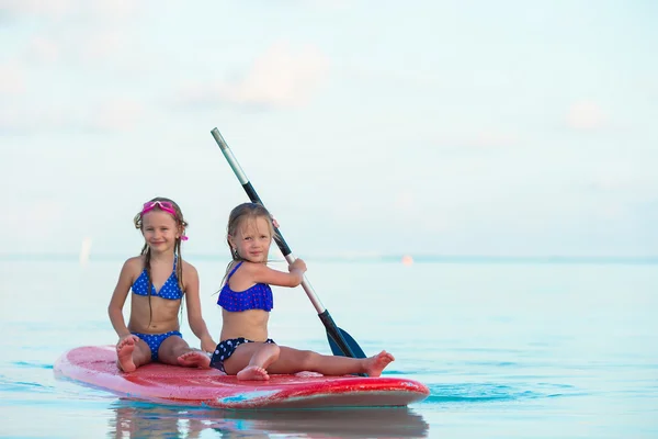 Kleine Mädchen schwimmen in den Sommerferien auf dem Surfbrett — Stockfoto