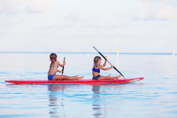 Kleine Mädchen schwimmen in den Sommerferien auf dem Surfbrett — Stockfoto