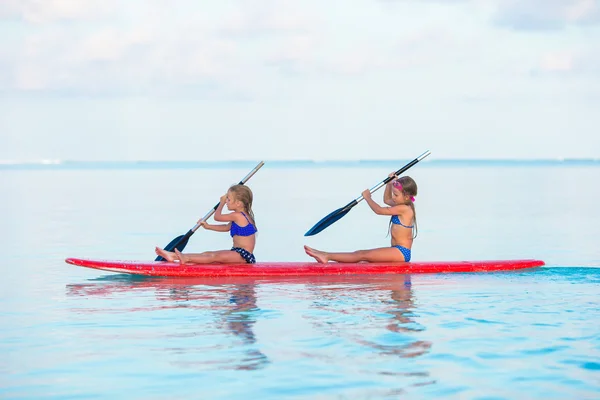 Kleine Mädchen schwimmen in den Sommerferien auf dem Surfbrett — Stockfoto
