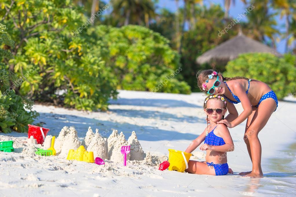 Happy little girls playing with beach toys during tropical vacation