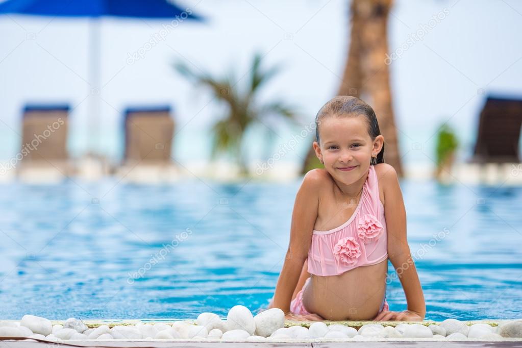 Smiling happy beautiful girl having fun in outdoor swimming pool