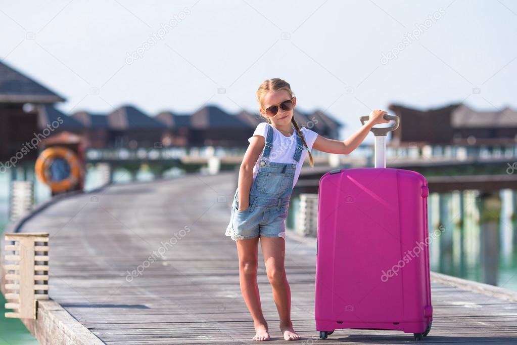 Little adorable girl with big luggage during summer vacation