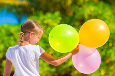 Balonlar ile plajda oynayan sevimli küçük kız