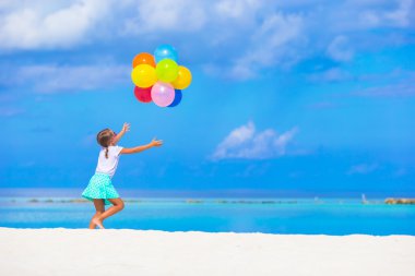 Balonlar ile plajda oynayan sevimli küçük kız