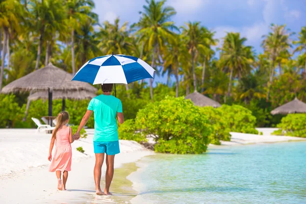 Vater und kleines Mädchen mit Regenschirm verstecken sich vor Sonne am Strand — Stockfoto