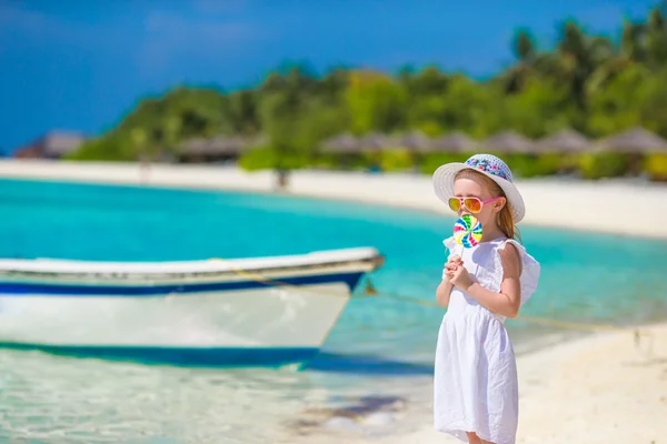Adorable little girl with lollipop on tropical beach — Stock Photo, Image