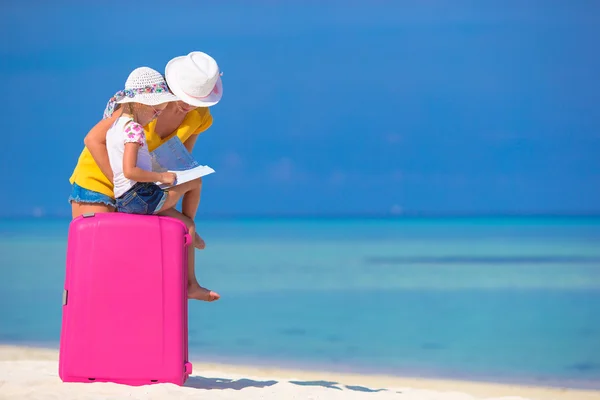Mother and little daughter with luggage and map on beach — Stock Photo, Image