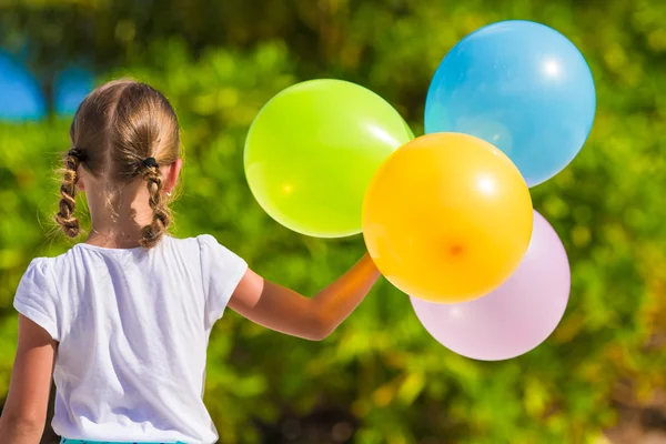 Adorable little girl playing with balloons at the beach — Stock Photo, Image