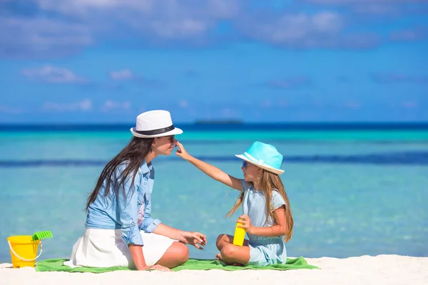 Pequena menina adorável aplicando creme solar para seu nariz mãe — Fotografia de Stock