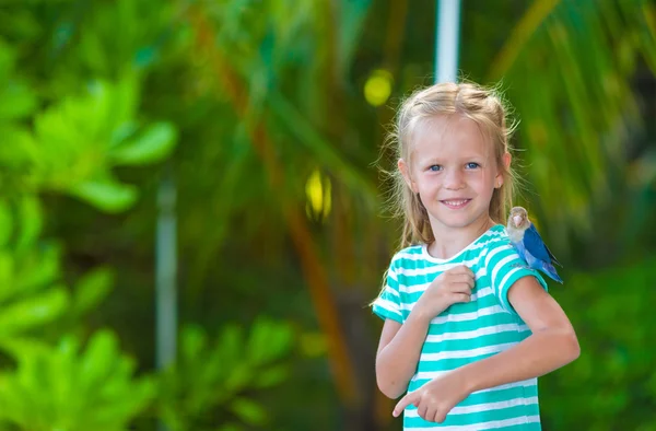 Adorable happy girl at beach with colorful little bird — Stock Photo, Image