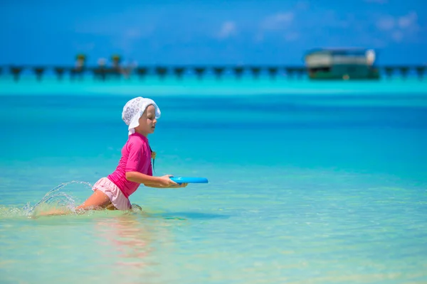 Malá dívka si hraje s létající disk na wnite beach — Stock fotografie