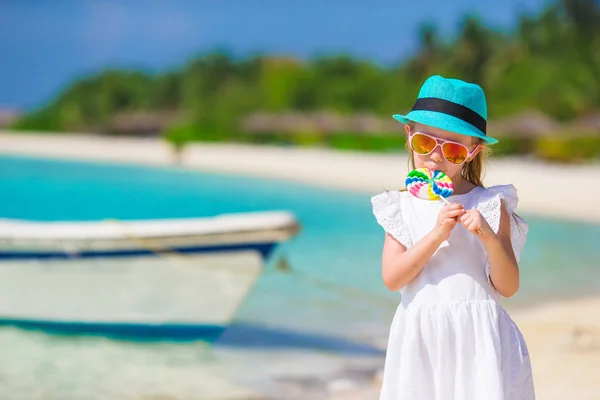 Adorable niña con piruleta en la playa tropical —  Fotos de Stock