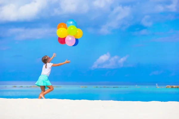 Adorável menina brincando com balões na praia — Fotografia de Stock