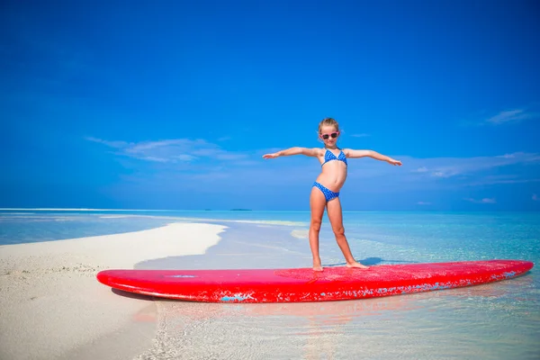 Kleines entzückendes Mädchen übt Surfposition am Strand — Stockfoto
