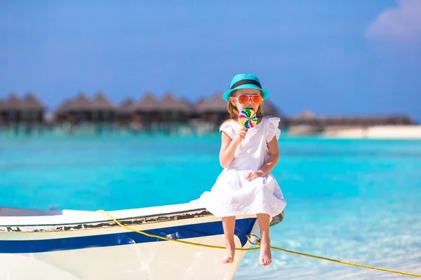Rozkošná holčička s lízátko sedí na lodi — Stock fotografie