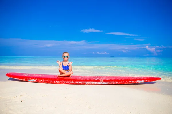 Little girl in yoga position meditating on surfboard — Stock Photo, Image