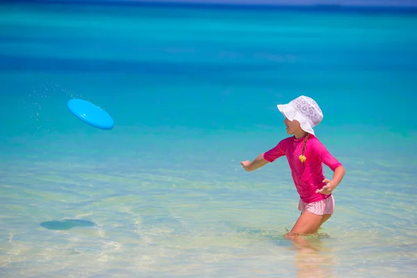 Liten flicka spelar med flygande skiva på wnite beach — Stockfoto