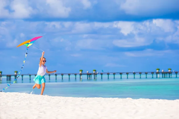 Gelukkig meisje spelen met vliegende kite op tropisch strand — Stockfoto