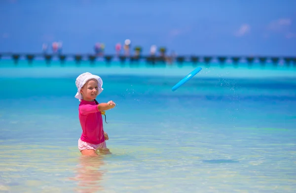 Niña jugando con disco volador en la playa wnite —  Fotos de Stock