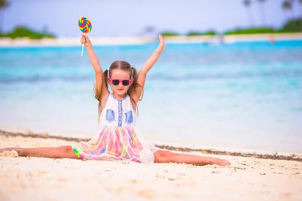 Menina adorável se divertir com pirulito na praia — Fotografia de Stock