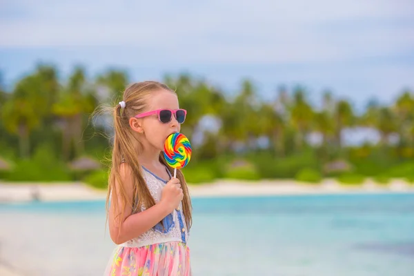 Menina adorável com pirulito na praia tropical — Fotografia de Stock