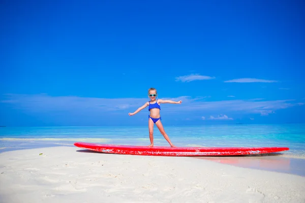 Urocze dziewczynki praktyki surfing pozycji na plaży — Zdjęcie stockowe