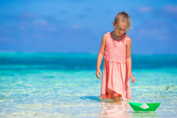 Adorável menina brincando com barco de papel no mar azul-turquesa — Fotografia de Stock