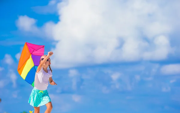 Piccola ragazza felice che gioca con aquilone volante sulla spiaggia tropicale — Foto Stock