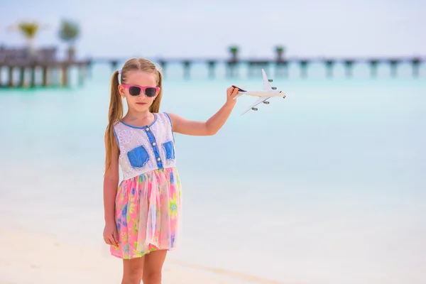 Bambina con aeroplano giocattolo in mano sulla spiaggia di sabbia bianca — Foto Stock