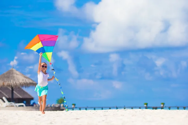 Niña feliz jugando con cometa voladora en la playa tropical —  Fotos de Stock