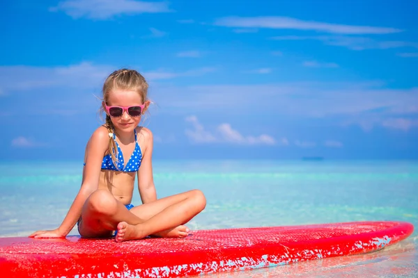 Little adorable girl on a surfboard in the turquoise sea — Stock Photo, Image