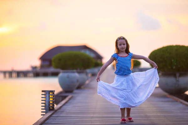 Силуэт очаровательной маленькой девочки на деревянном причале на закате — стоковое фото