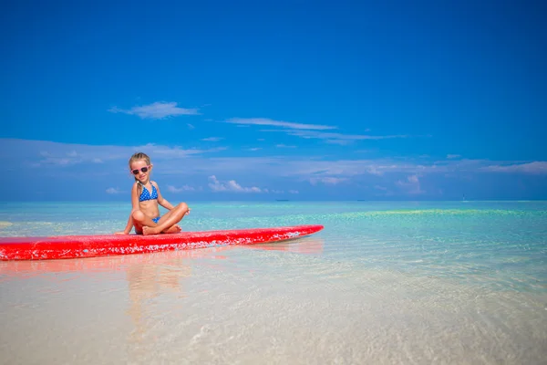 Little adorable girl on a surfboard in the turquoise sea — Stock Photo, Image
