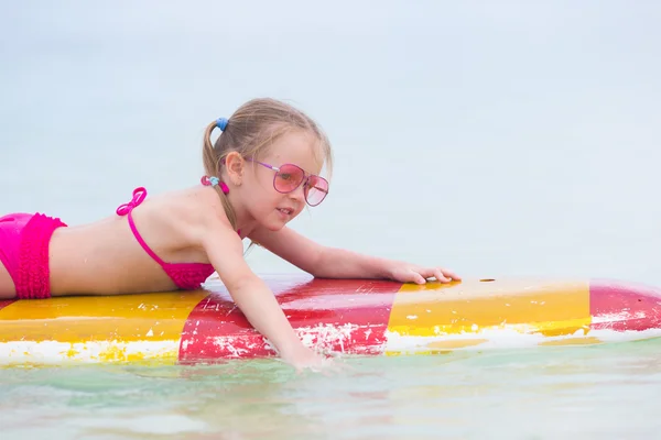 Little adorable girl on a surfboard in the turquoise sea — Stock Photo, Image