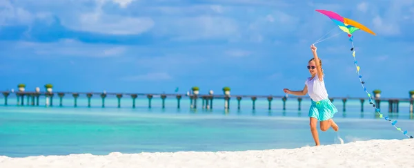 Pequena menina feliz brincando com pipa voadora na praia tropical — Fotografia de Stock