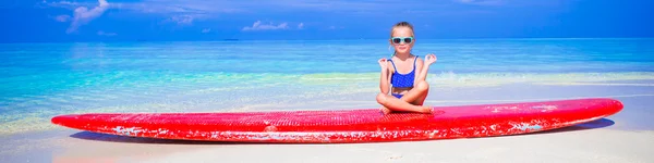 Little girl in yoga position meditating on surfboard — Stock Photo, Image