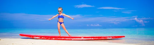 Rozkošná holčička praxi surfování postavení na pláži — Stock fotografie
