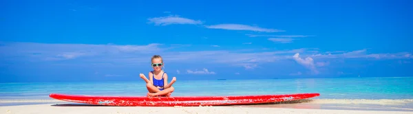 Niña en posición de yoga meditando sobre tabla de surf — Foto de Stock