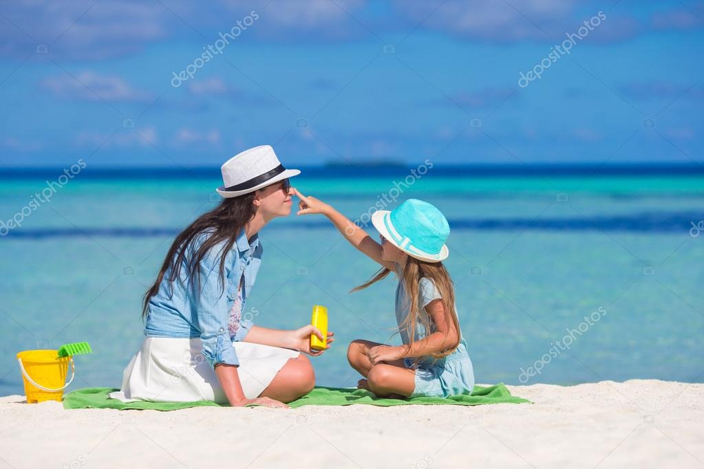 Little girl applying sun cream to her mother nose