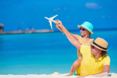 Young man and little girl with miniature of airplane at beach clipart