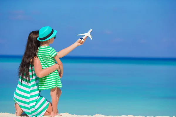 Young woman and little girl with miniature of airplane at beach — Stock Photo, Image