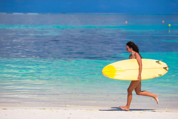 Felice giovane donna surf che corre in spiaggia con una tavola da surf — Foto Stock