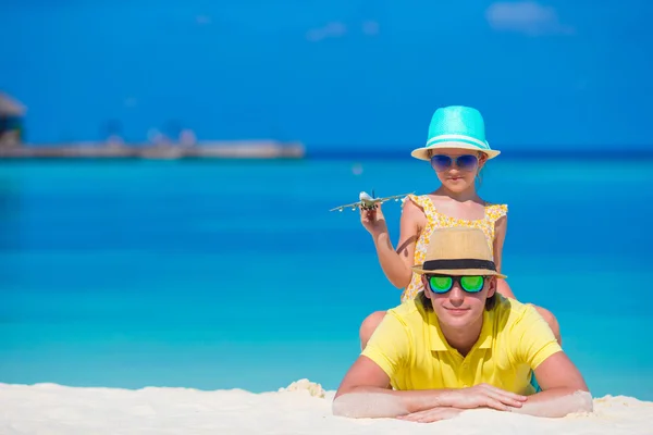 Junger Mann und kleines Mädchen mit Miniatur eines Flugzeugs am Strand — Stockfoto