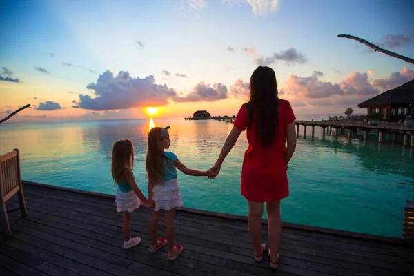 Silhouette of young mother and two her little girls at sunset — Stock Photo, Image