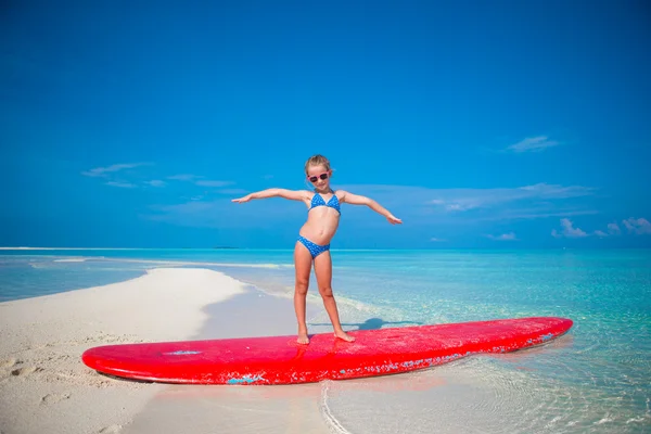 Kleines entzückendes Mädchen übt Surfposition am Strand — Stockfoto